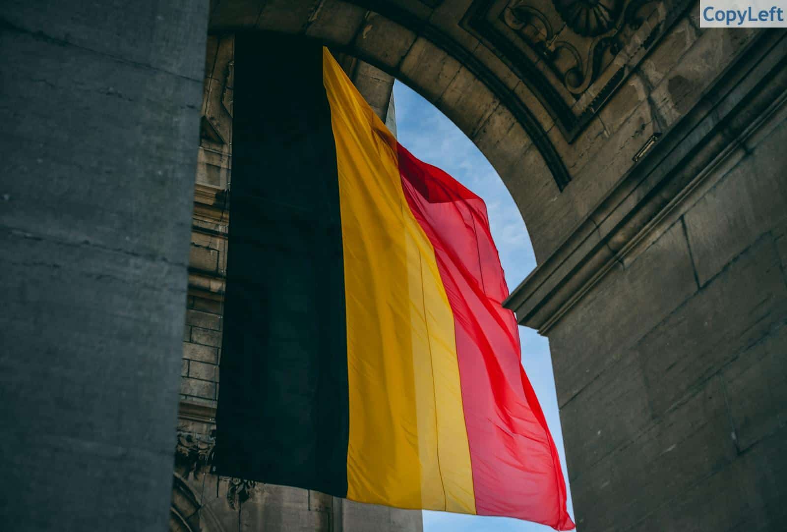 Vibrant Belgian flag under iconic archway in Brussels, symbolizing national pride.