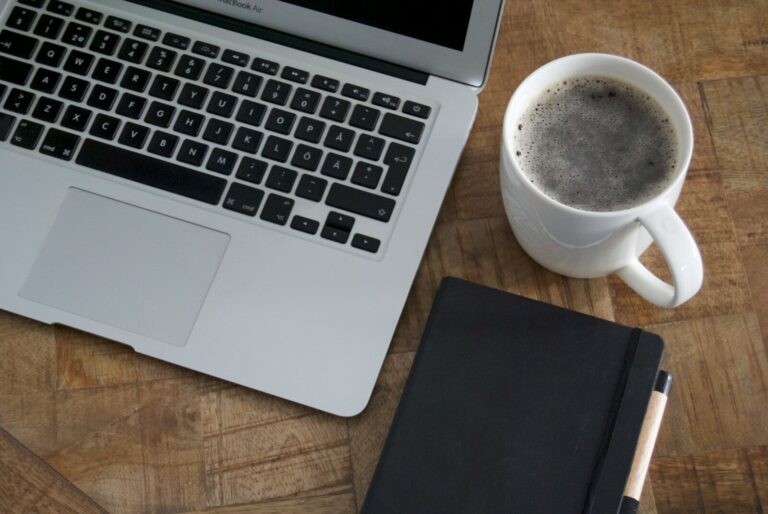 Taza de café junto a una libreta y un bolígrafo en la mesa de la redacción